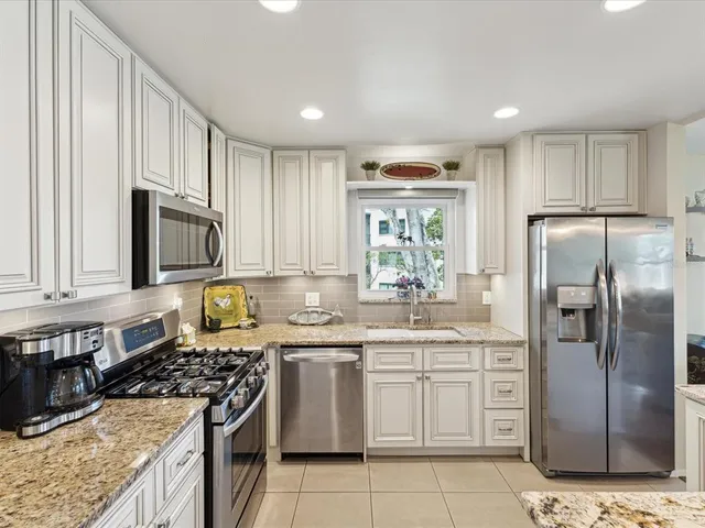 a kitchen with stainless steel appliances granite countertop a stove a sink dishwasher a refrigerator and cabinets with wooden floor