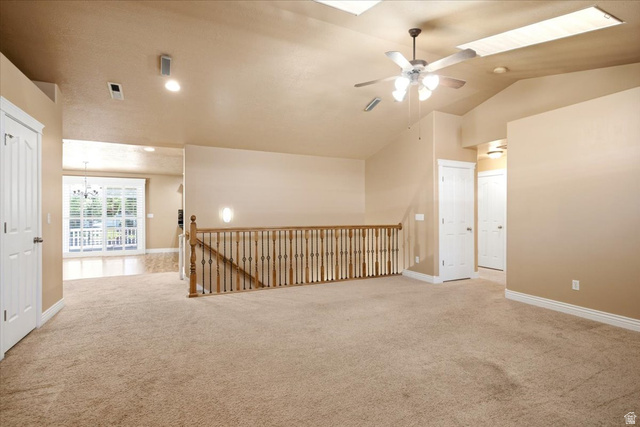 1089 West 2325th Street North Layton, UT 84041 - Photo 13 of 40 Spacious carpeted area featuring a wood staircase with iron balusters, vaulted ceilings with skylights, and a ceiling fan with integrated lighting