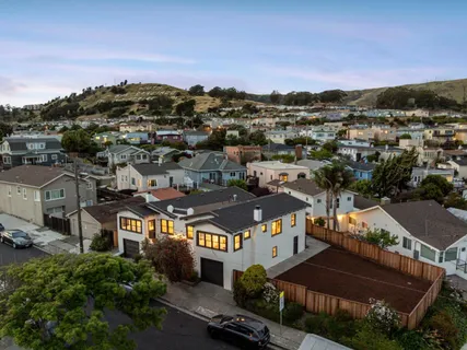 an aerial view of a city with lots of residential buildings and mountain view in back