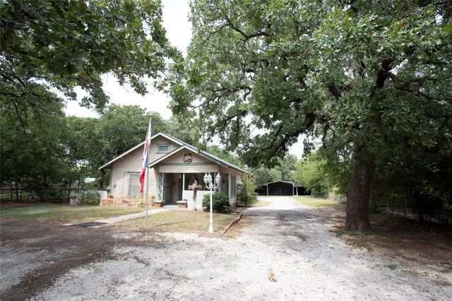 a front view of a house with a yard and large trees
