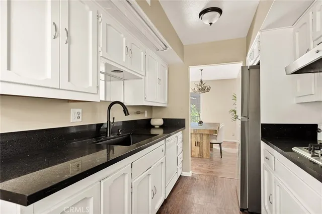 a kitchen with granite countertop a sink stainless steel appliances and cabinets