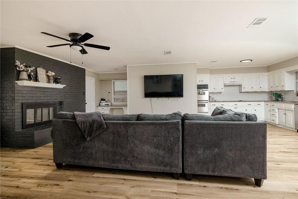 117 Kathryn Street Sanger, TX 76266 - Photo 7 of 40 Living area with ornamental molding, light wood-type flooring, a brick fireplace, and a ceiling fan