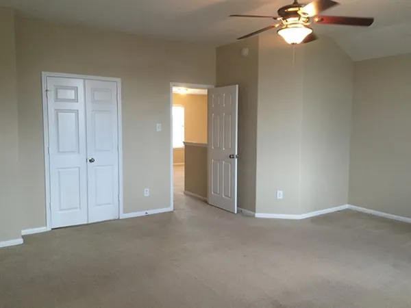 a view of an empty room with a chandelier fan