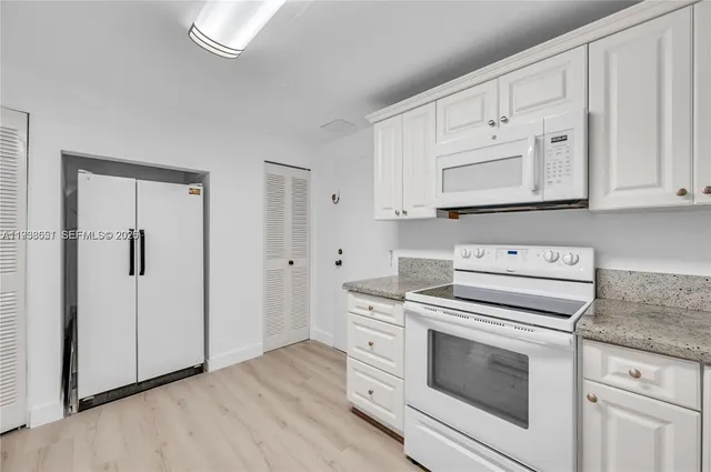 a kitchen with white cabinets and white appliances