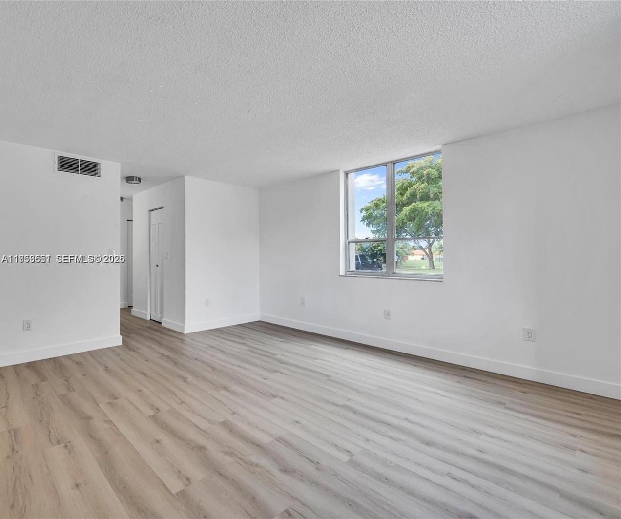 6861 Southwest 147th Avenue, Unit 1H Miami, FL 33193 - Photo 19 of 30 an empty room with wooden floor and windows