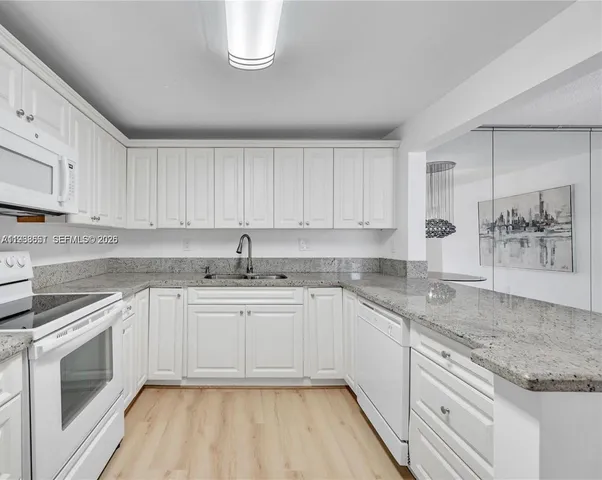a kitchen with granite countertop white cabinets and white appliances