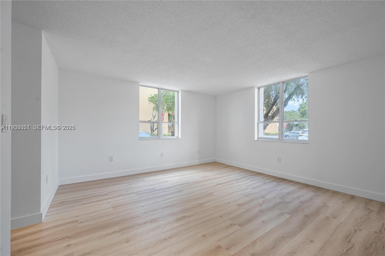 6861 Southwest 147th Avenue, Unit 1H Miami, FL 33193 - Photo 7 of 30 an empty room with wooden floor and windows