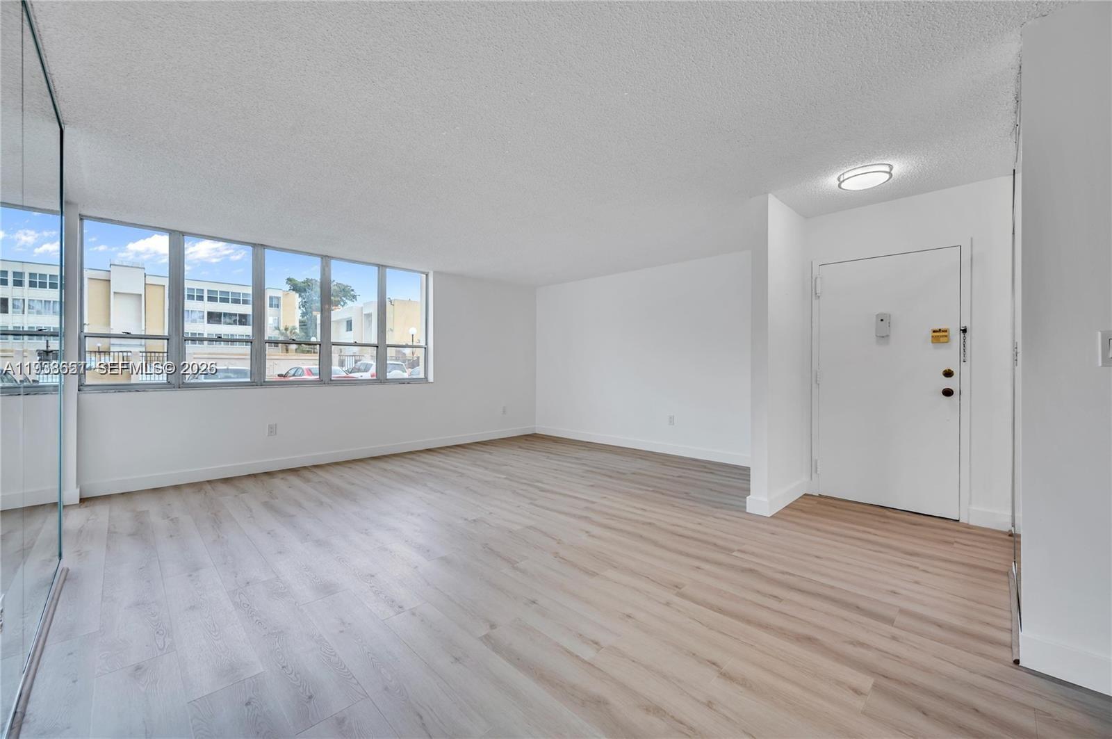 6861 Southwest 147th Avenue, Unit 1H Miami, FL 33193 - Photo 9 of 30 a view of an empty room with wooden floor and a window