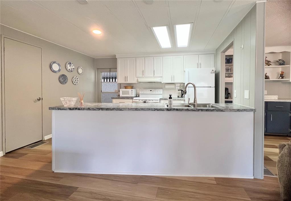 1100 South Belcher Road, Unit 657 Largo, FL 33771 - Photo 27 of 81 a kitchen with kitchen island granite countertop a sink cabinets and wooden floor