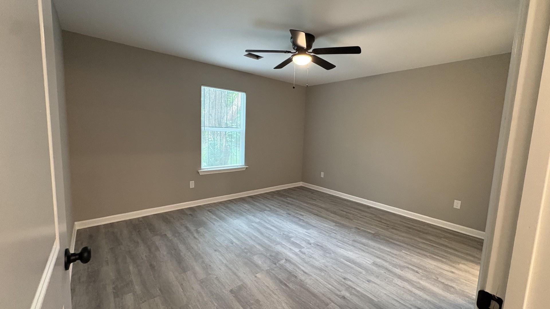 643 Kent Street Memphis, TN 38111 - Photo 6 of 14 Spacious interior room featuring wood-finish flooring, neutral wall tones, a single window, white baseboards, and a ceiling fan with integrated lighting