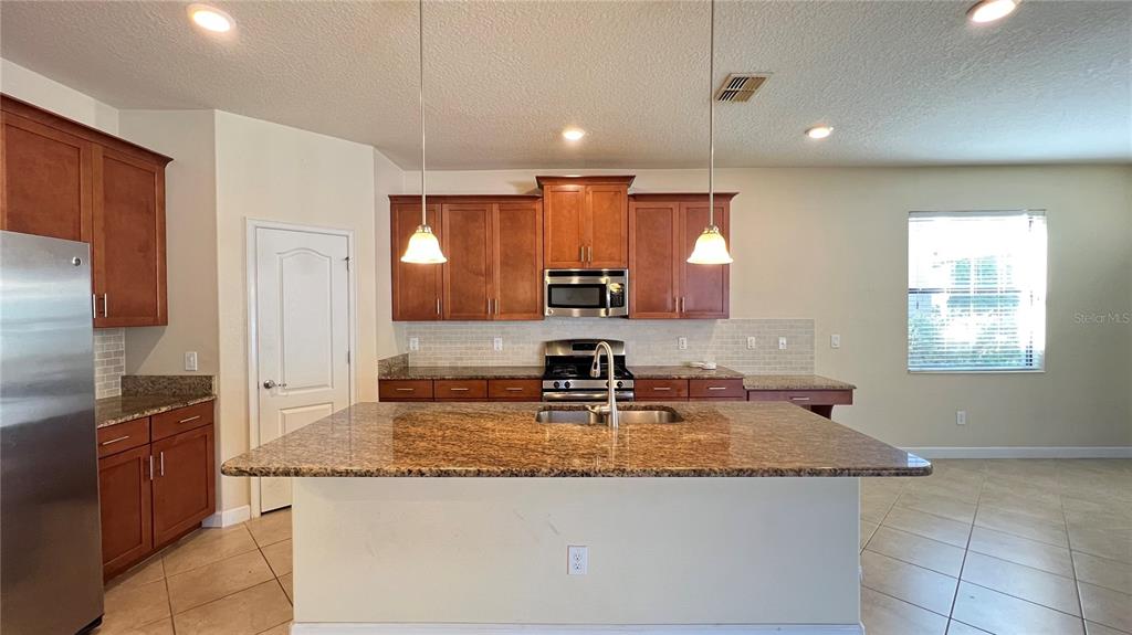 15401 Porter Road Winter Garden, FL 34787 - Photo 29 of 59 a kitchen with kitchen island granite countertop a sink a counter top space appliances and cabinets