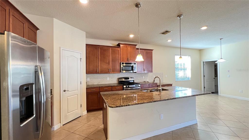 15401 Porter Road Winter Garden, FL 34787 - Photo 30 of 59 a kitchen with stainless steel appliances granite countertop a refrigerator a sink and a stove