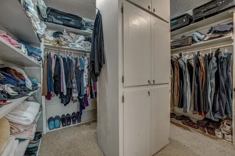 a view of walk in closet with clothes and shoes