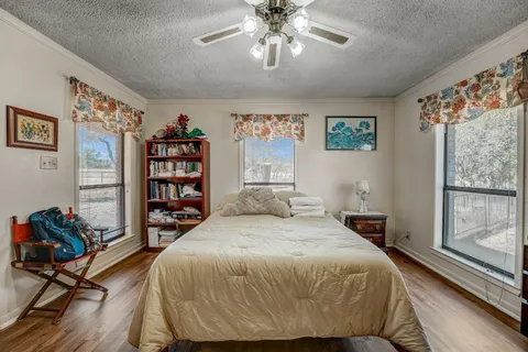 a bedroom with a bed a dresser and a large window