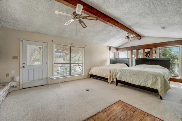 a spacious bedroom with a bed a chandelier and large window