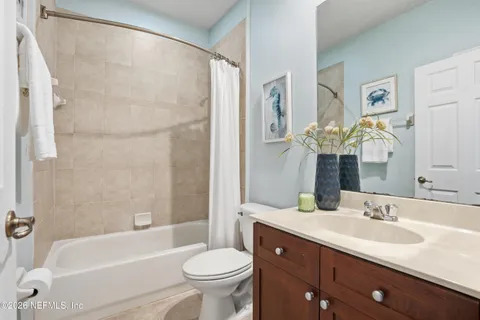 a bathroom with a bathtub shower sink vanity mirror and toilet