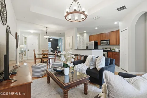 a living room with furniture kitchen view and a chandelier
