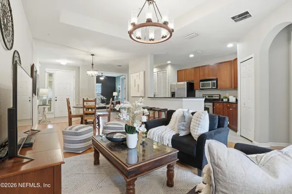 a living room with furniture kitchen view and a chandelier