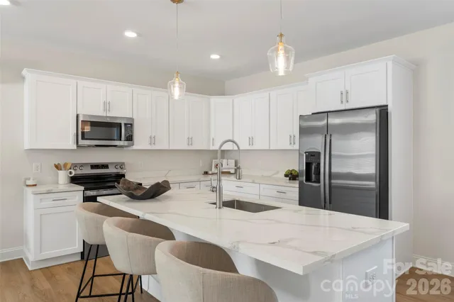 a kitchen with a refrigerator a stove a sink and white cabinets