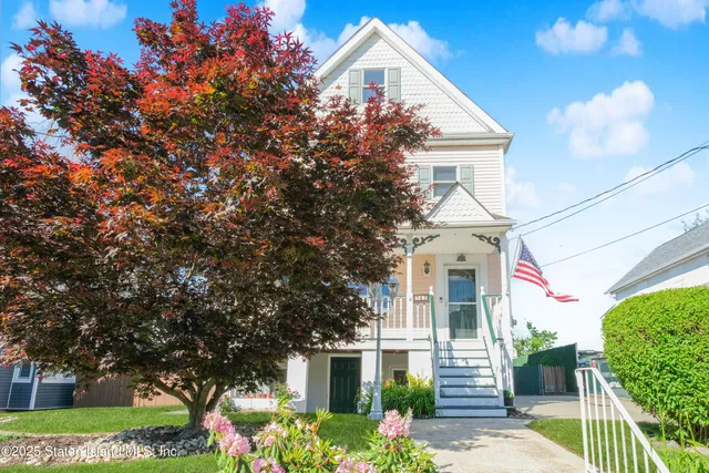 a front view of a white house with a yard and potted plants