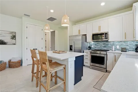 a kitchen with stainless steel appliances kitchen island granite countertop a stove a sink dishwasher a refrigerator and a dining table with wooden floor