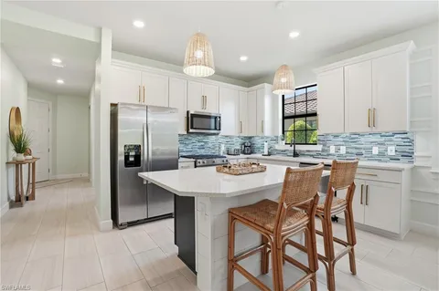 a kitchen with stainless steel appliances kitchen island granite countertop a sink a stove a refrigerator cabinets and chairs