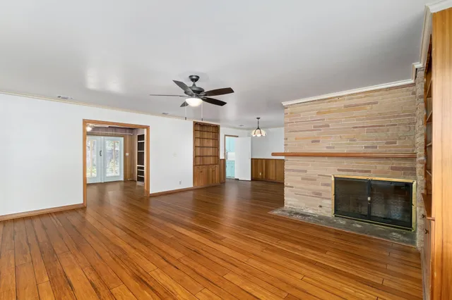 an empty room with wooden floor fireplace and windows