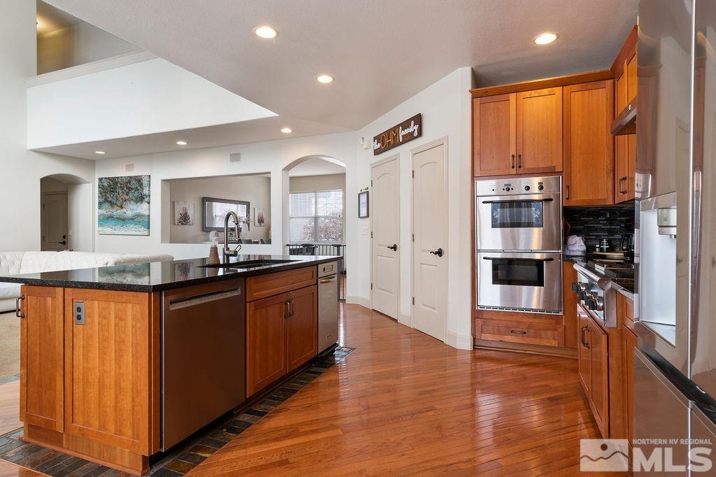 9985 Moccasin Court Reno, NV 89521 - Photo 11 of 40 a large kitchen with stainless steel appliances granite countertop a refrigerator a sink dishwasher a stove and white countertops with wooden floor