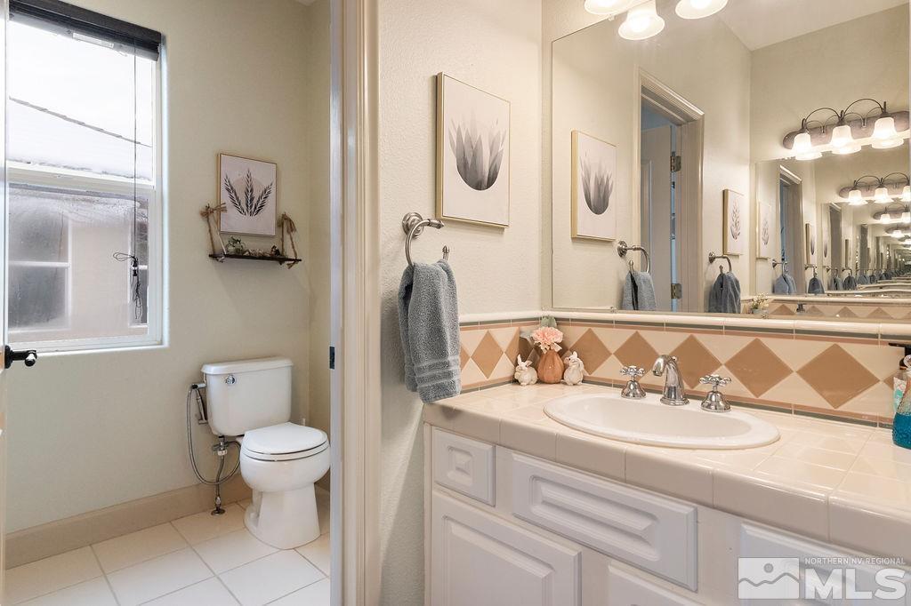 9985 Moccasin Court Reno, NV 89521 - Photo 25 of 40 a bathroom with a granite countertop toilet sink and mirror
