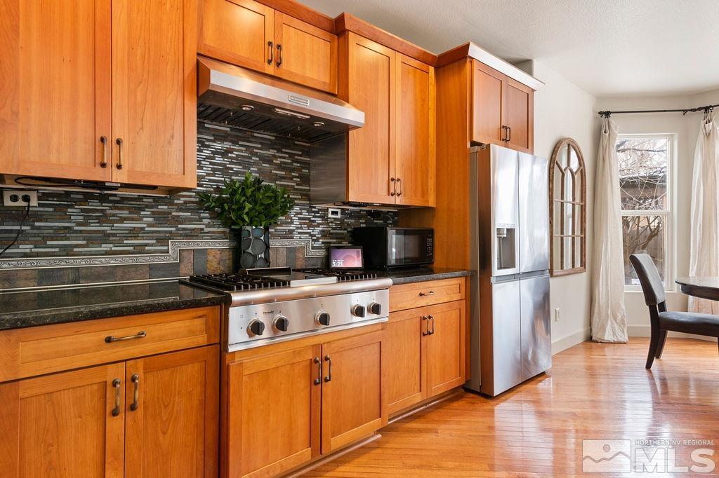 9985 Moccasin Court Reno, NV 89521 - Photo 10 of 40 a kitchen with stainless steel appliances granite countertop a refrigerator a stove and white cabinets with wooden floor