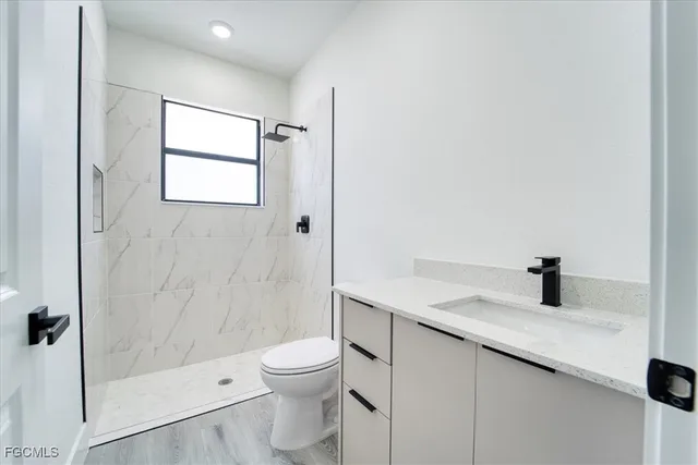 a bathroom with a granite countertop sink a toilet and shower