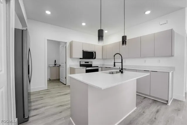 a kitchen with a sink stainless steel appliances and wooden floor