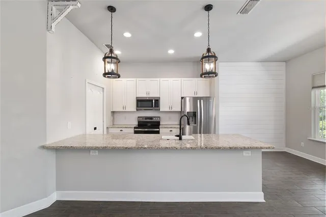 a kitchen with stainless steel appliances kitchen island granite countertop a refrigerator a stove and a sink