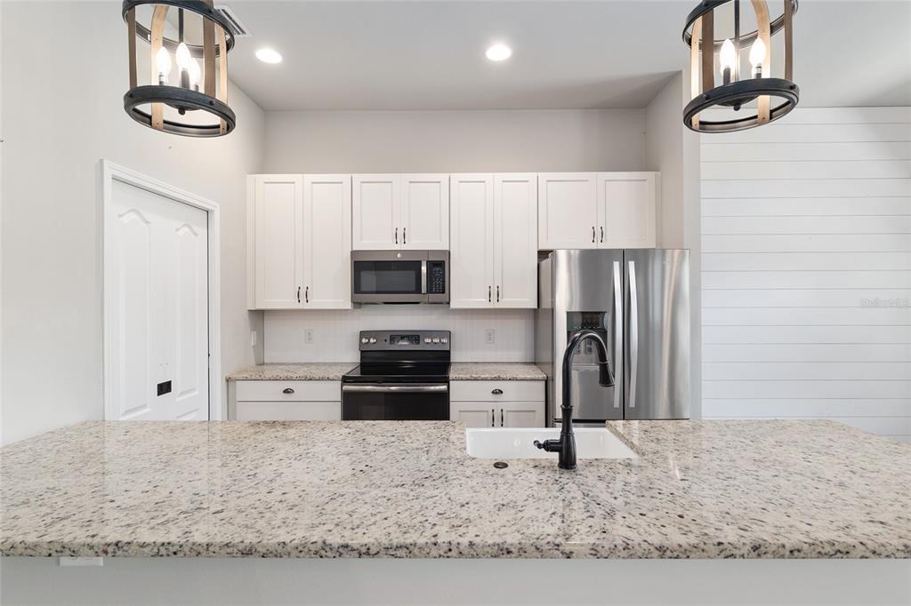 2556 Southwest 118th Terrace Gainesville, FL 32608 - Photo 18 of 72 a kitchen with stainless steel appliances kitchen island granite countertop a refrigerator a stove and a sink