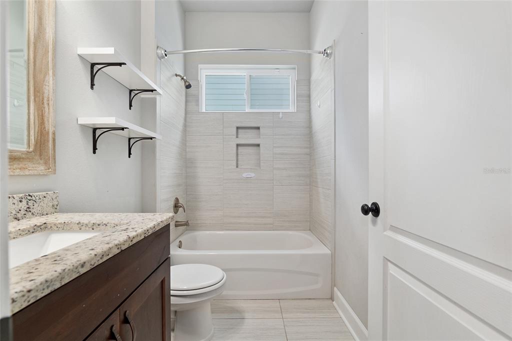 2556 Southwest 118th Terrace Gainesville, FL 32608 - Photo 43 of 72 a bathroom with a granite countertop sink a toilet and bathtub