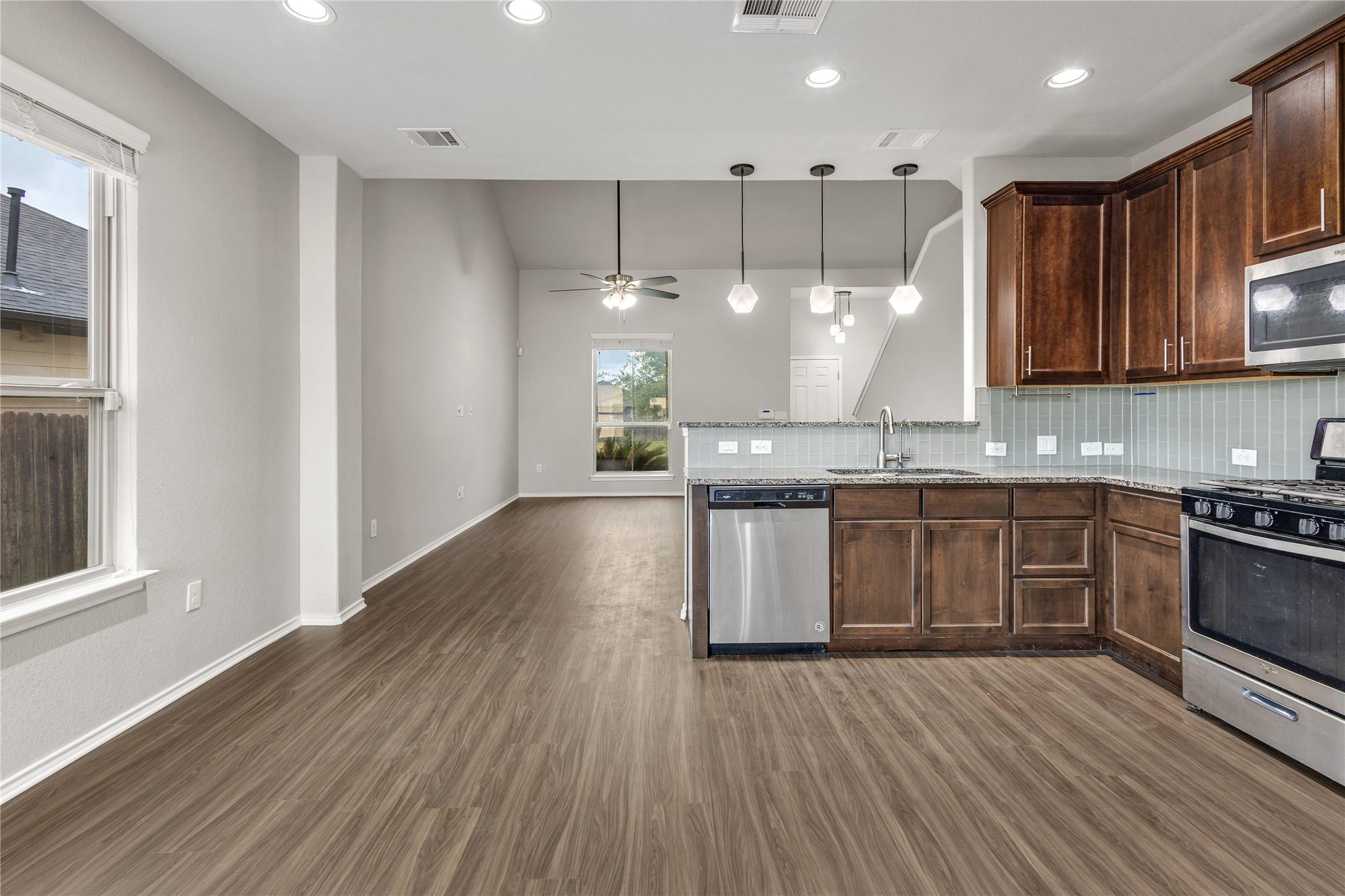 397 Limerick Road Buda, TX 78610 - Photo 6 of 33 Rich espresso-toned cabinetry provides a beautiful contrast against the stainless steel appliances and the sleek, sea-glass green tile backsplash adds a pop of modern color and texture that ties the whole space together.