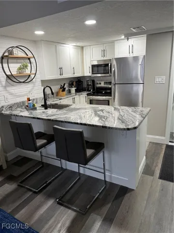 a kitchen with kitchen island granite countertop a sink cabinets and stainless steel appliances