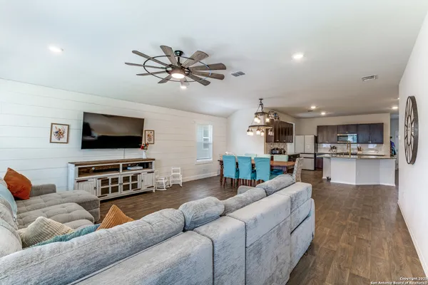 a kitchen with stainless steel appliances granite countertop a stove top oven a sink dishwasher a dining table and chairs with wooden floor