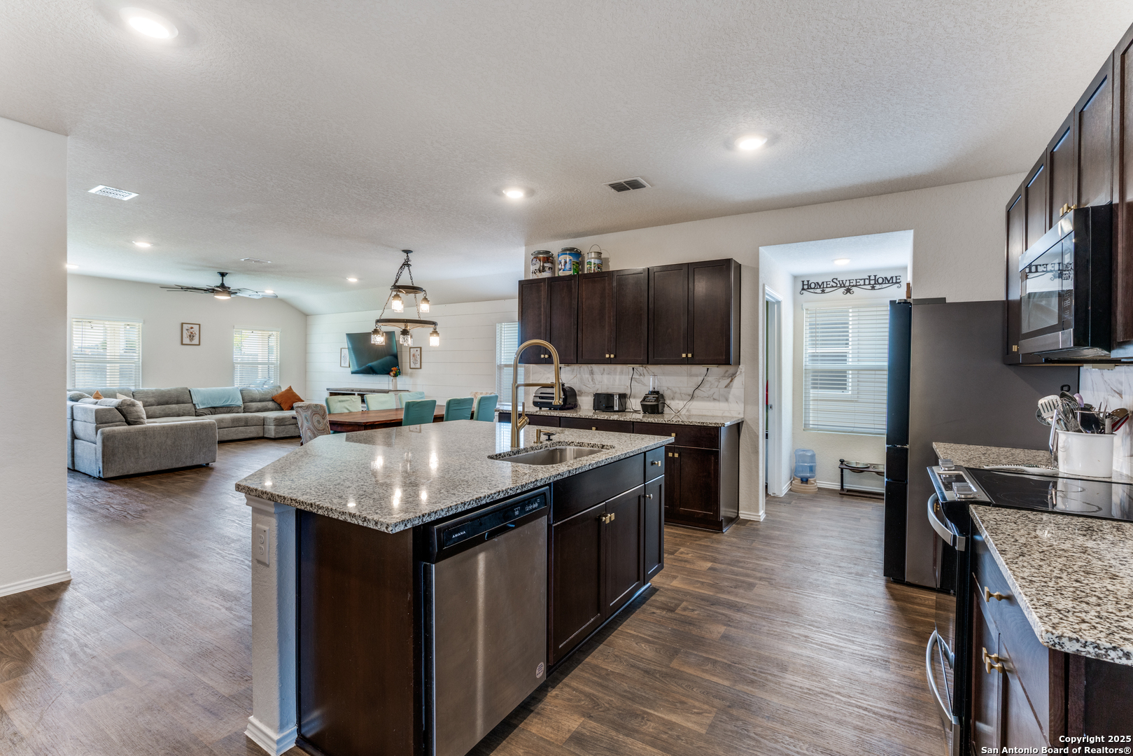 816 Indigo Way Seguin, TX 78155 - Photo 7 of 25 a kitchen with stainless steel appliances granite countertop a stove top oven a sink dishwasher a dining table and chairs with wooden floor