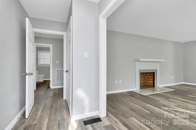 a view of a livingroom with wooden floor and a fireplace