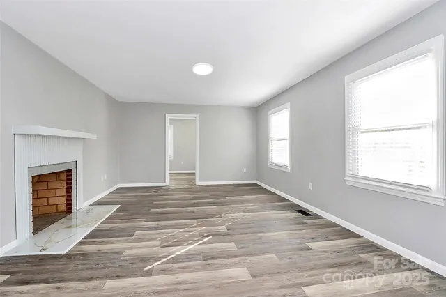 a view of an empty room with a window and fireplace