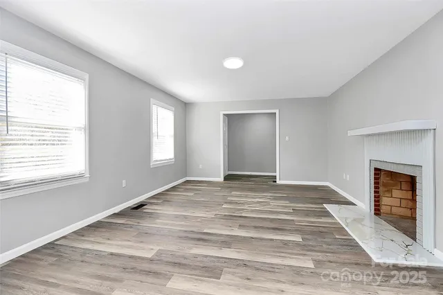 a view of an empty room with window and fire place