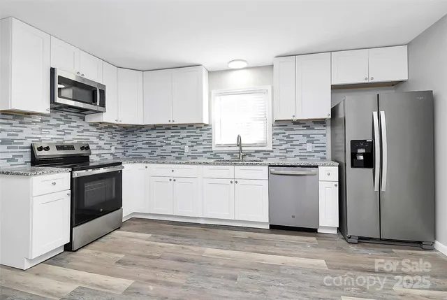 a kitchen with granite countertop a refrigerator stove and microwave
