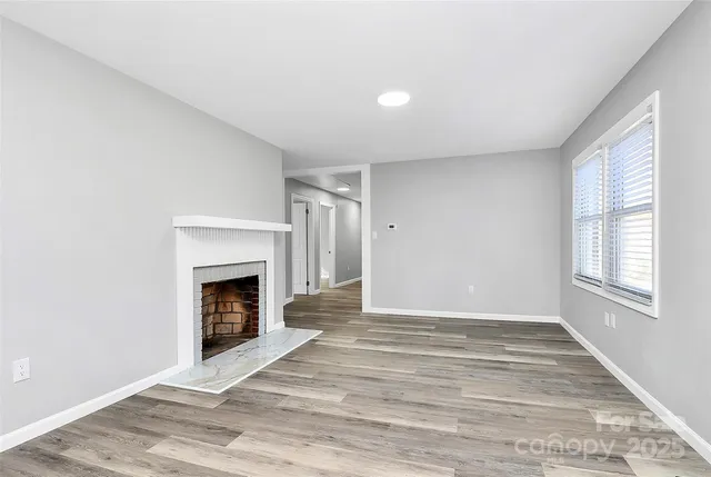 a view of an empty room with a fireplace and a window