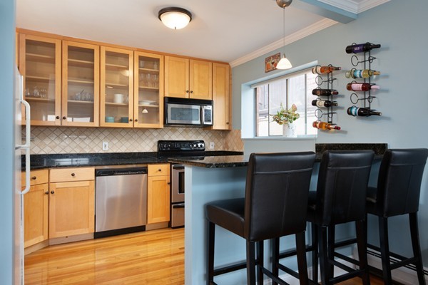 259 Beacon Street, Unit 71 Boston, MA 02116 - Photo 3 of 9 a kitchen with stainless steel appliances granite countertop a stove top oven a sink dishwasher and cabinets with wooden floor