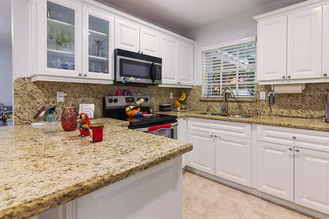 a kitchen with granite countertop a sink dishwasher stove and cabinets