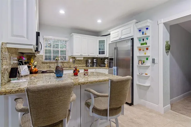 a kitchen with stainless steel appliances granite countertop a refrigerator a sink a stove a dining table and chairs