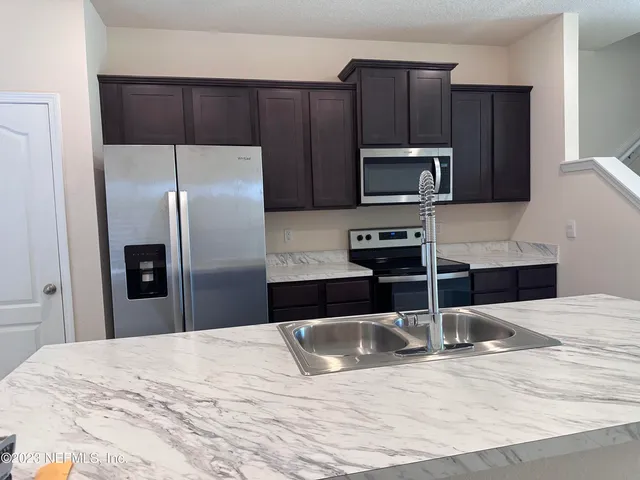 a kitchen with granite countertop a refrigerator microwave and sink