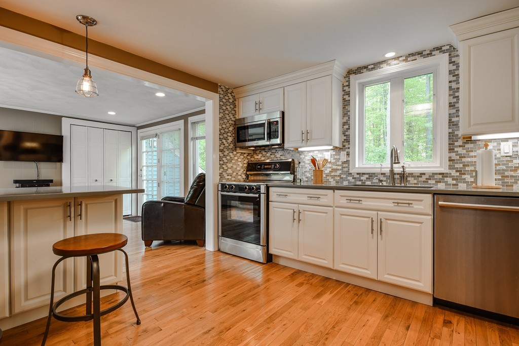 27 Stonebridge Road Wayland, MA 01778 - Photo 5 of 19 a kitchen with stainless steel appliances granite countertop a stove top oven a sink dishwasher a dining table and chairs with wooden floor