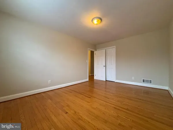 a view of an empty room with wooden floor and window